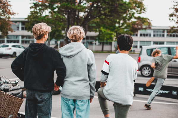 3 drenge står med ryggen til og ser på en anden dreng som laver boldtriks
